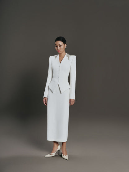 Woman wearing a white suit against a gray background