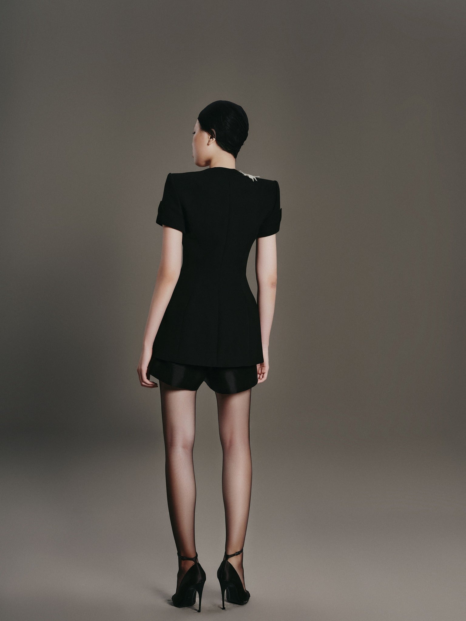 Woman wearing a black dress against a gray background