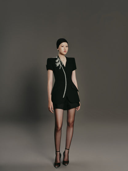 Model wearing a black outfit with a floral detail on a gray background