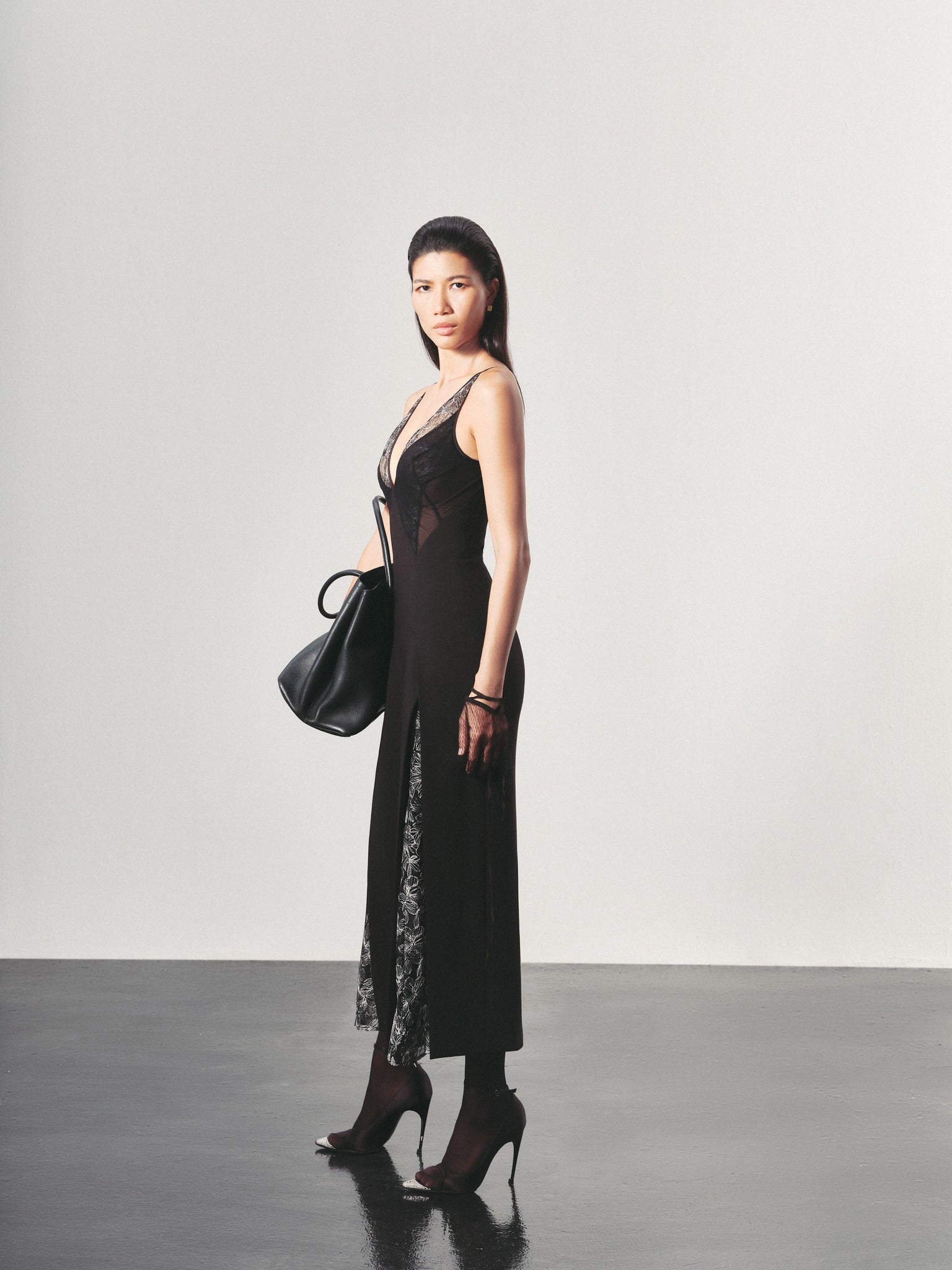 Woman wearing a black dress with sheer panels against a plain background