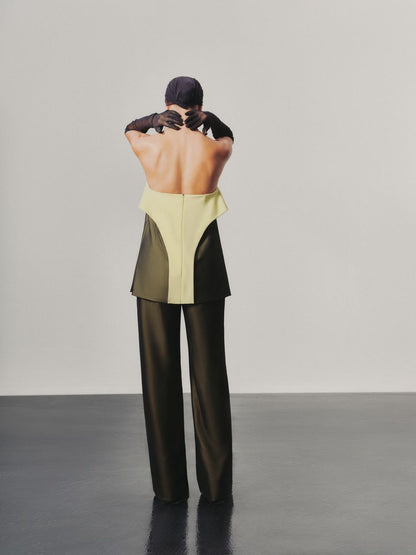 Person wearing a two-tone outfit with a yellow top and black pants on a plain background