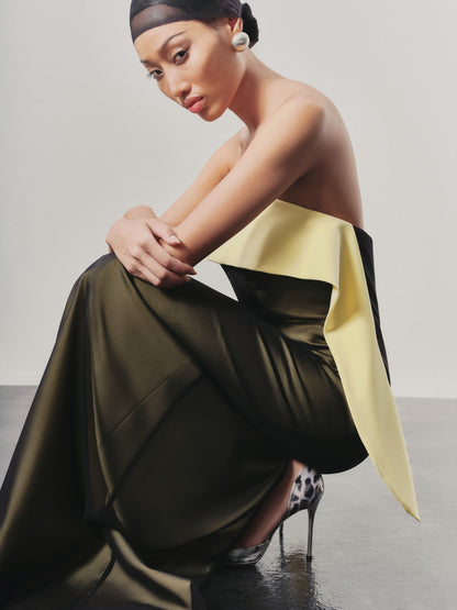 Woman in a stylish outfit with a yellow top and green skirt against a plain background