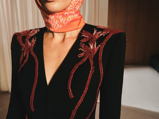 Black outfit with red floral embroidery worn by a model, with a blurred background