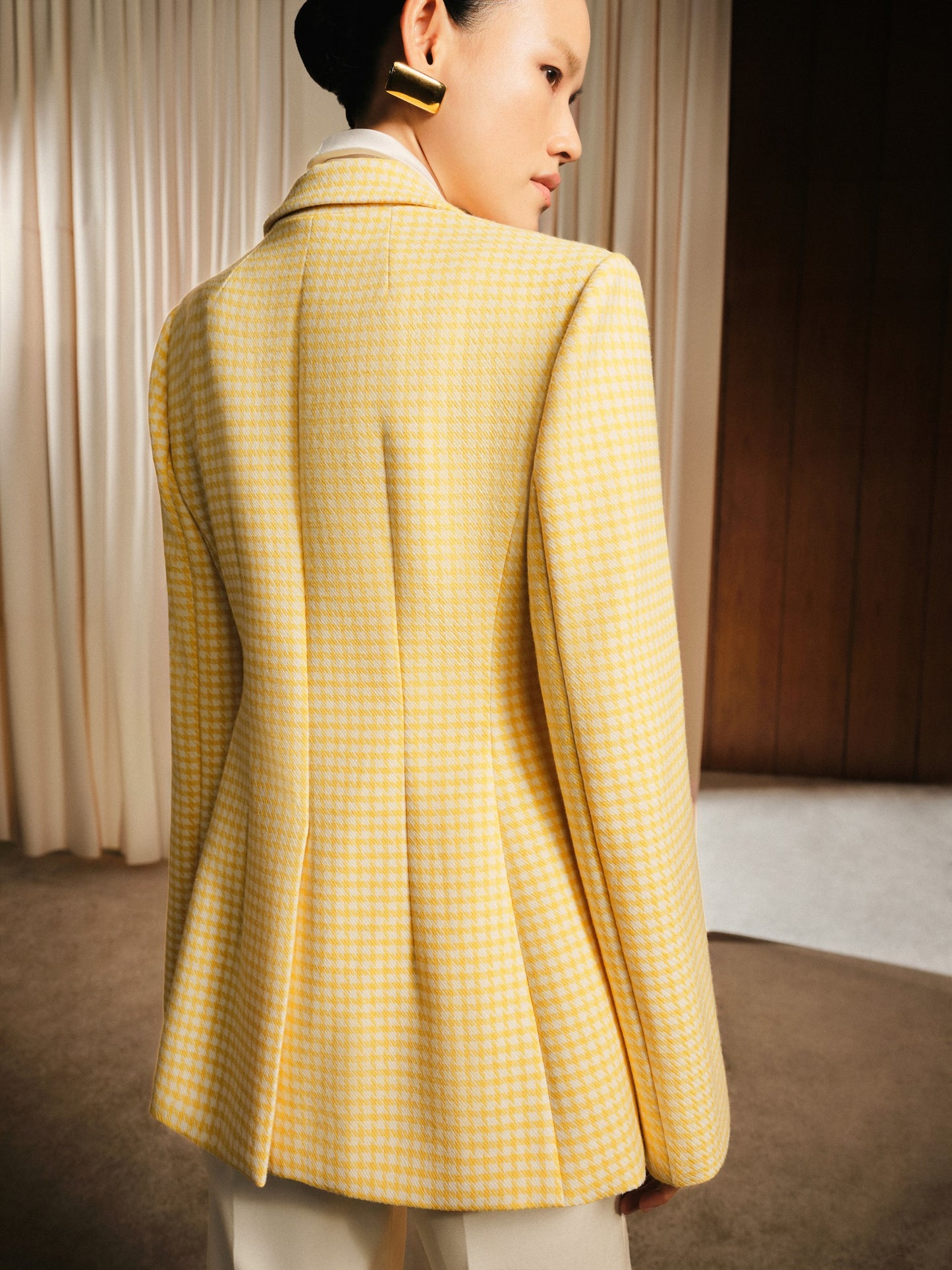 Person wearing a yellow checkered blazer in an indoor setting