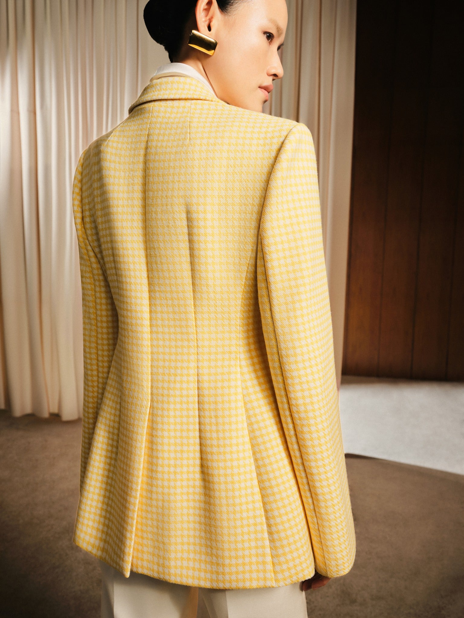 Person wearing a yellow checkered blazer in an indoor setting