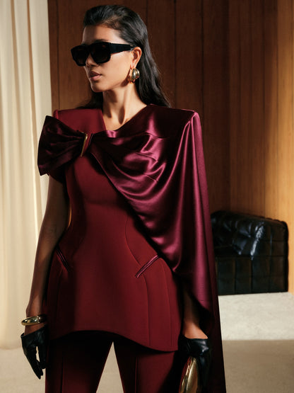 Woman wearing a burgundy outfit with a cape in an indoor setting