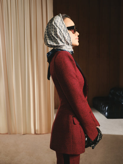 Person wearing a red suit and patterned headscarf in an indoor setting