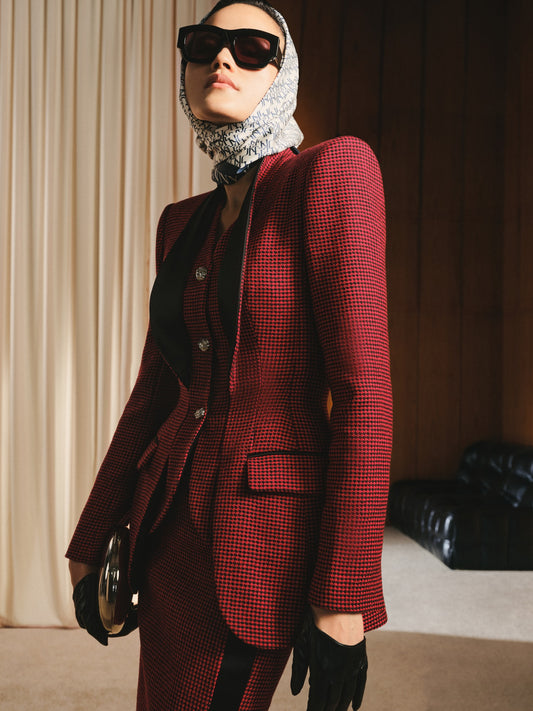 Person wearing a red checkered suit with sunglasses and gloves indoors.