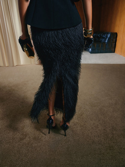 Person wearing a black feathered skirt and high heels in an indoor setting.