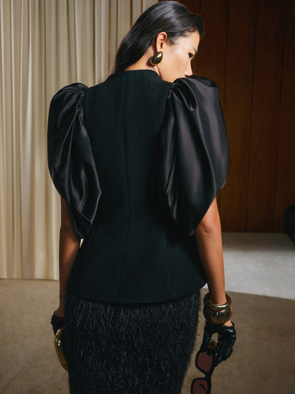 Woman wearing a black dress with puffed sleeves in an indoor setting