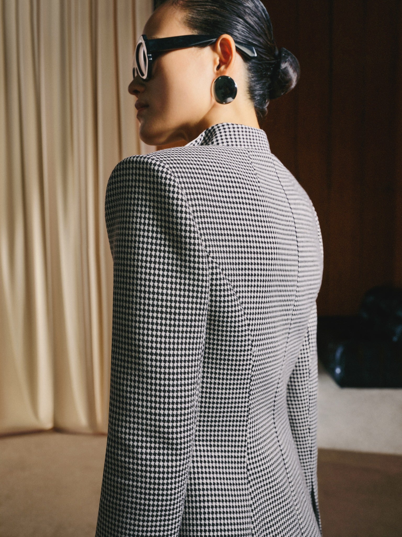 Person wearing a black and white checkered blazer in an indoor setting.
