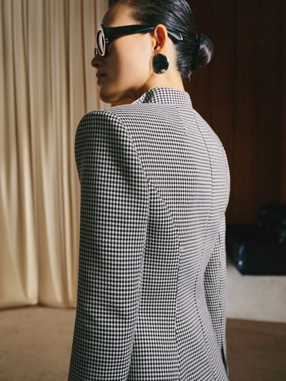 Person wearing a black and white checkered blazer in an indoor setting.