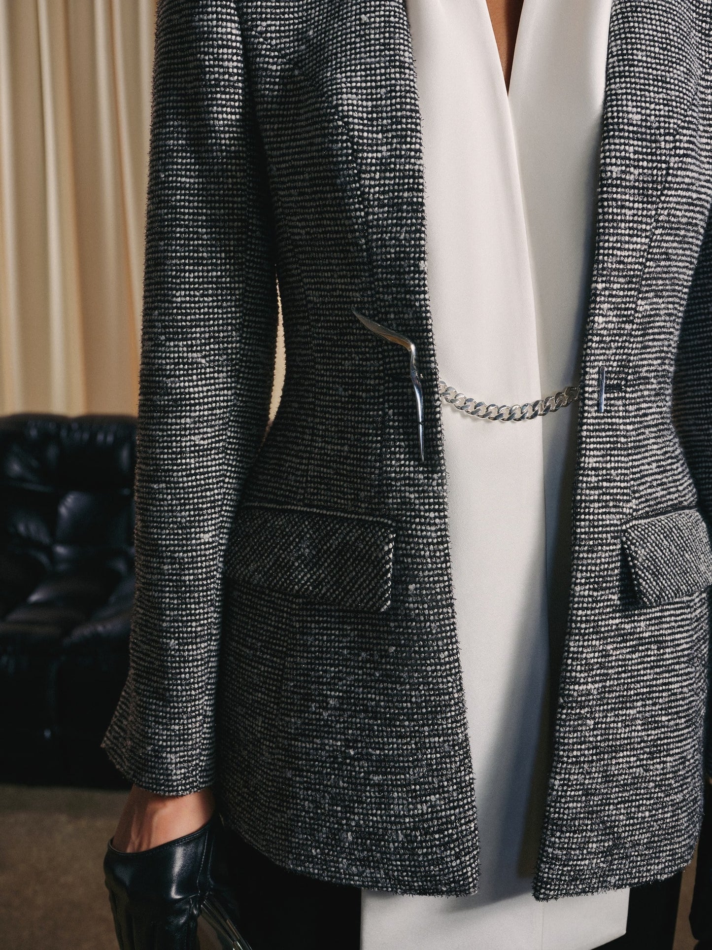 Person wearing a textured gray blazer over a white top with a blurred background