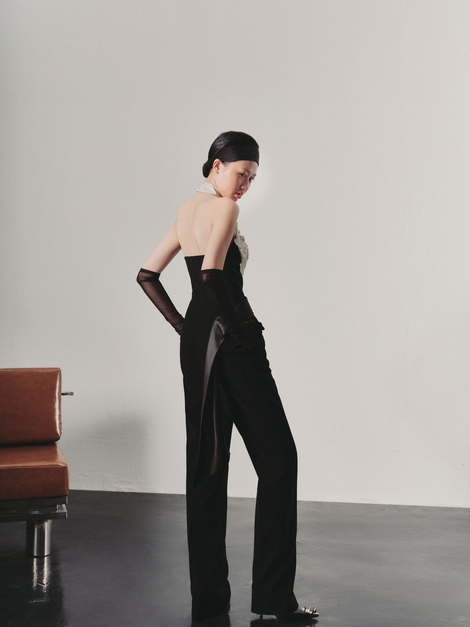 Woman in a black outfit standing against a plain background