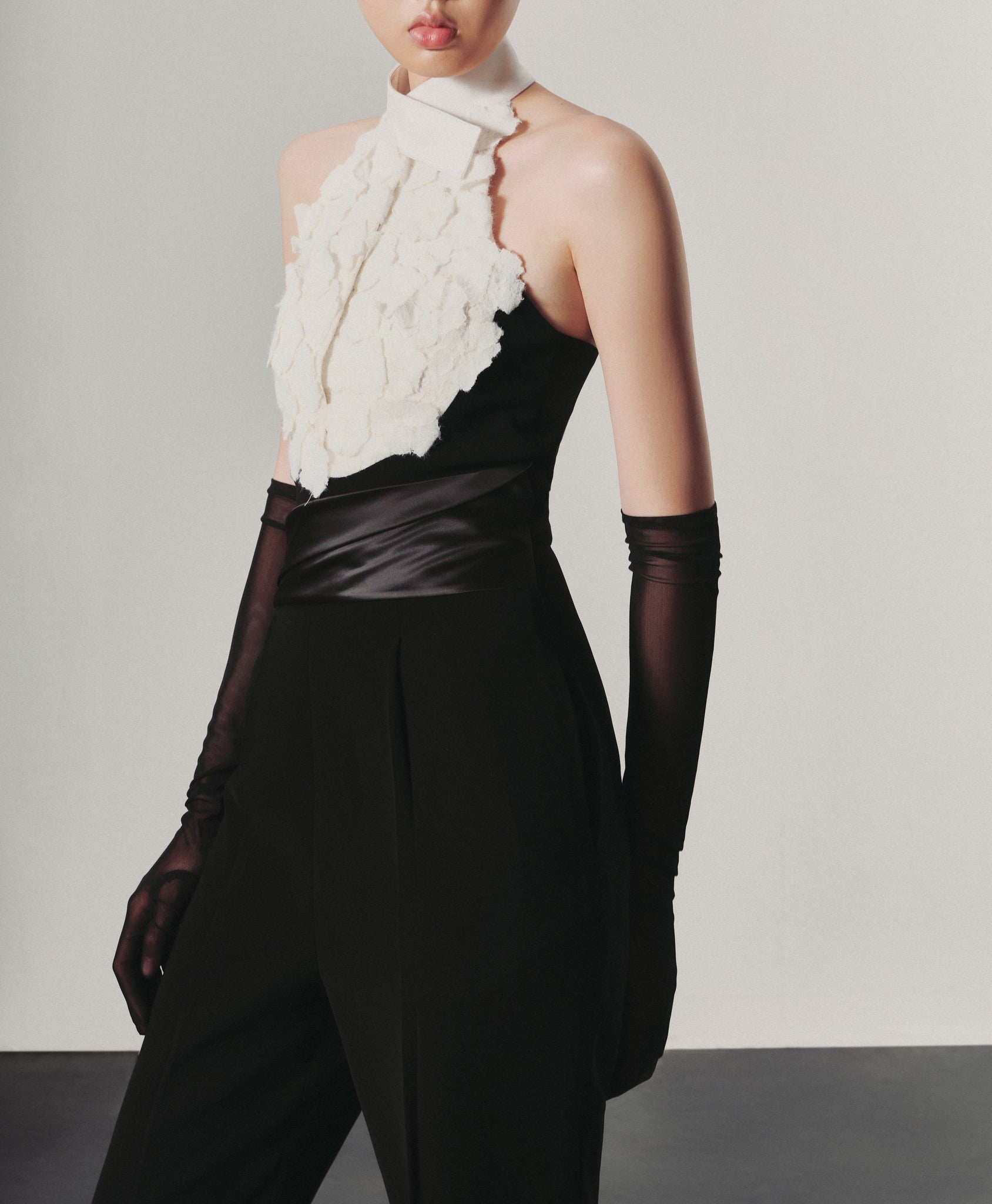 Person wearing a black and white outfit with a textured white top and high-waisted black pants.