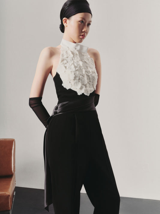 Woman wearing a black outfit with a white floral top against a plain background