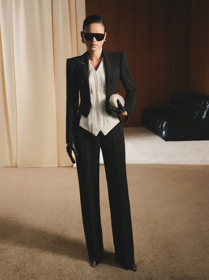 Person wearing a black suit and sunglasses in an indoor setting