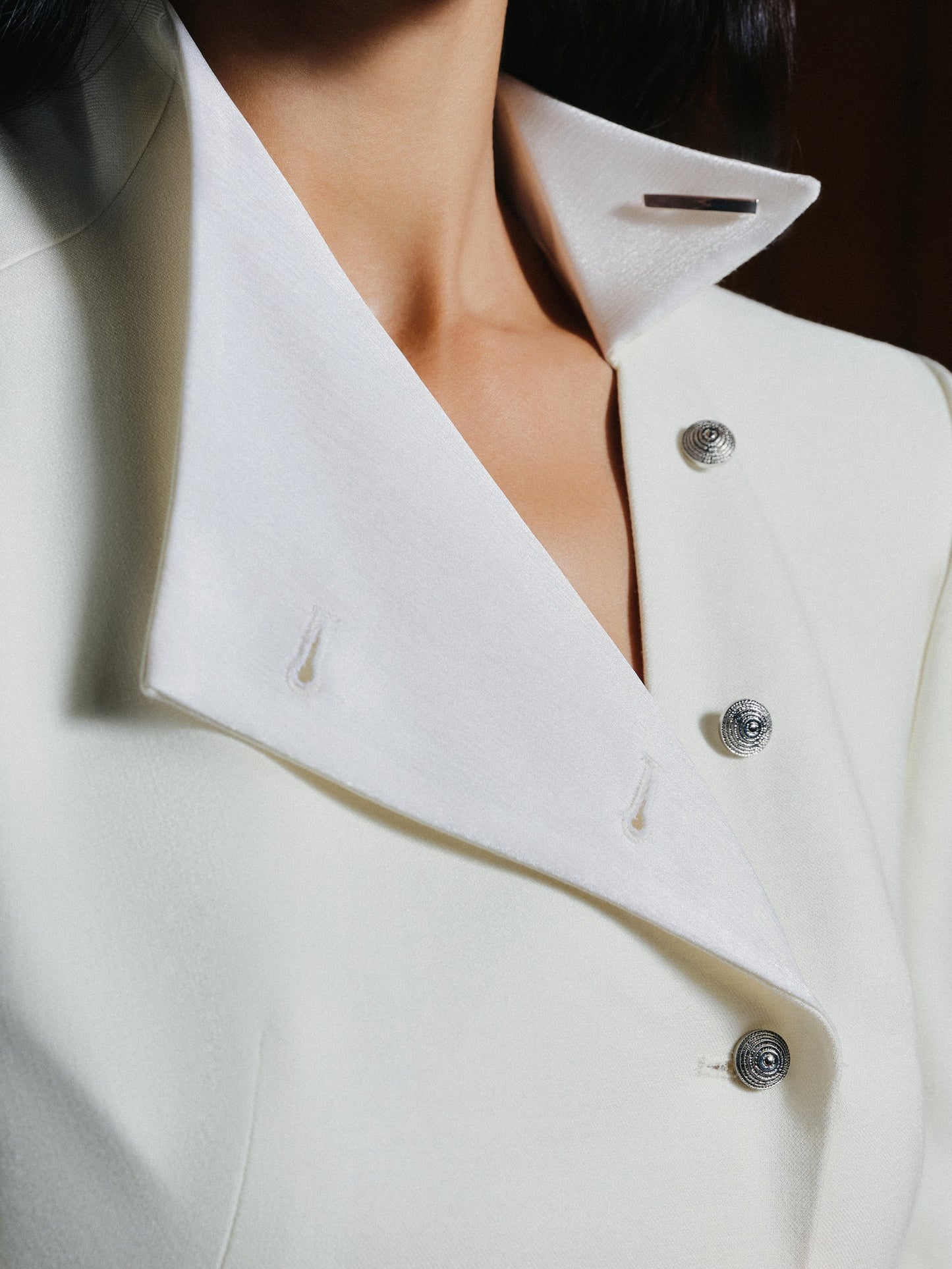 Close-up of a white coat with buttons on a dark background