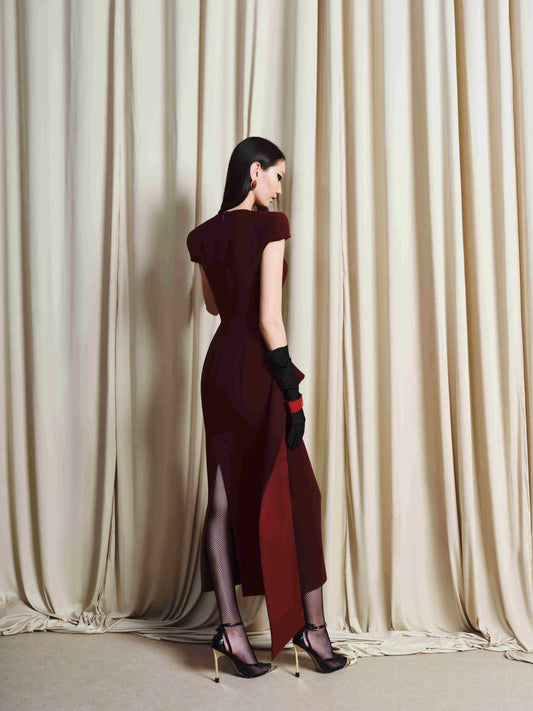 Woman in a burgundy dress standing in front of beige curtains