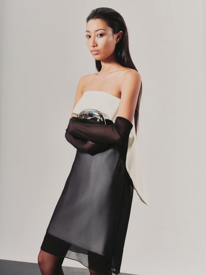 Woman wearing a strapless dress with black sleeves against a plain background