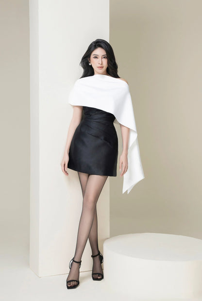 Woman wearing a white off-shoulder top and black leather skirt against a plain background