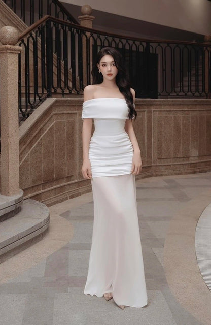 Woman in a white off-shoulder gown standing in an elegant interior setting.