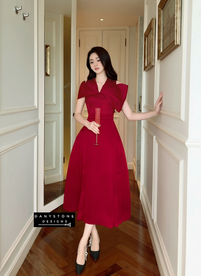 Woman in a red dress standing in a hallway with white walls and wooden floor.