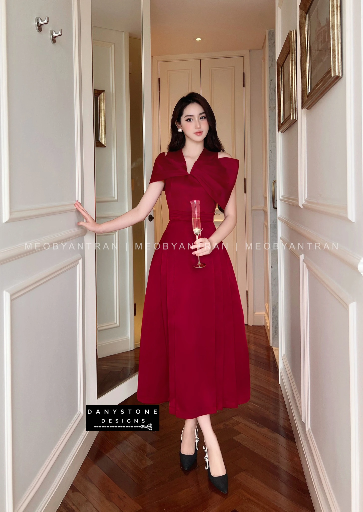 Model showcasing chic wedding party flared dress in red - holding a champagne glass