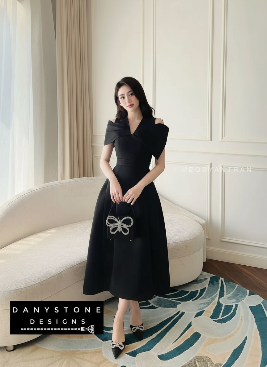 Woman in a black dress standing in a stylish room with a sofa and decorative rug.