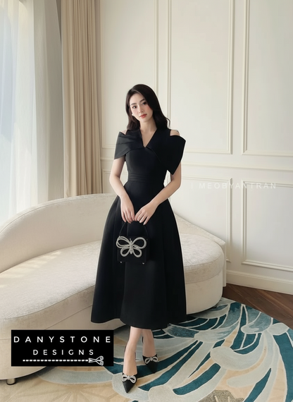 Woman in a black dress standing in a stylish room with a sofa and decorative rug.