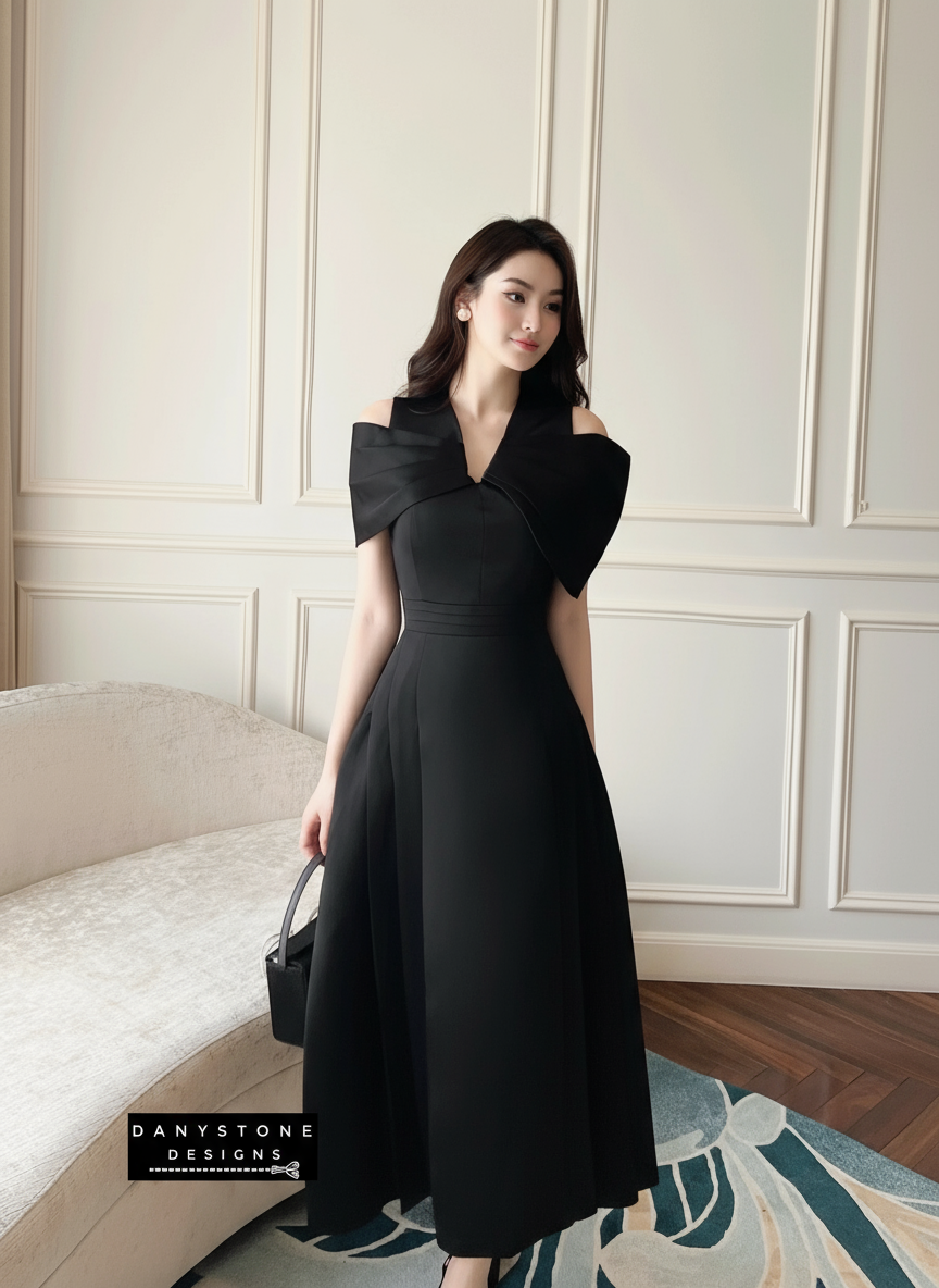 Woman wearing a black dress in an elegant room with a sofa and decorative wall.