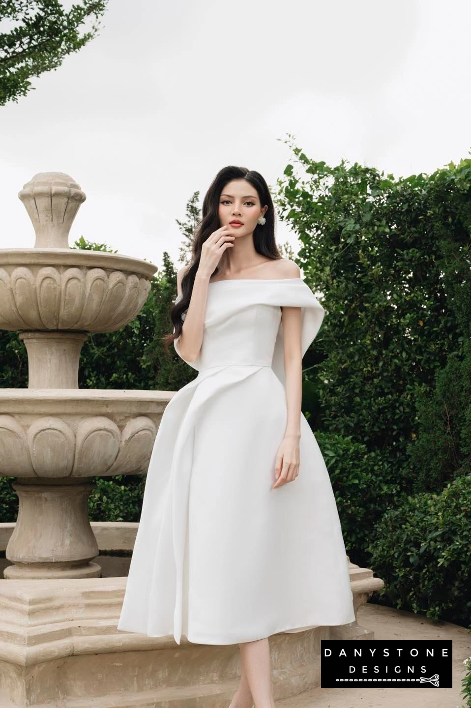 Detailed look at flared hem of stylish one-sided pleated dress in white