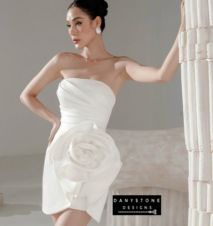 Close-up of floral accent on strapless bodycon dress with pleated waist in white