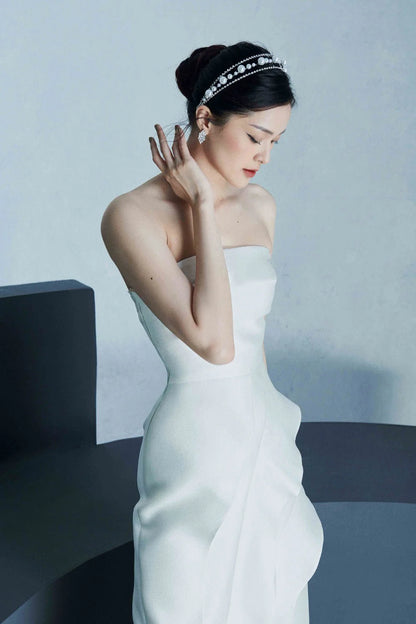 Model showcasing simple and elegant ruffled front strapless dress in white