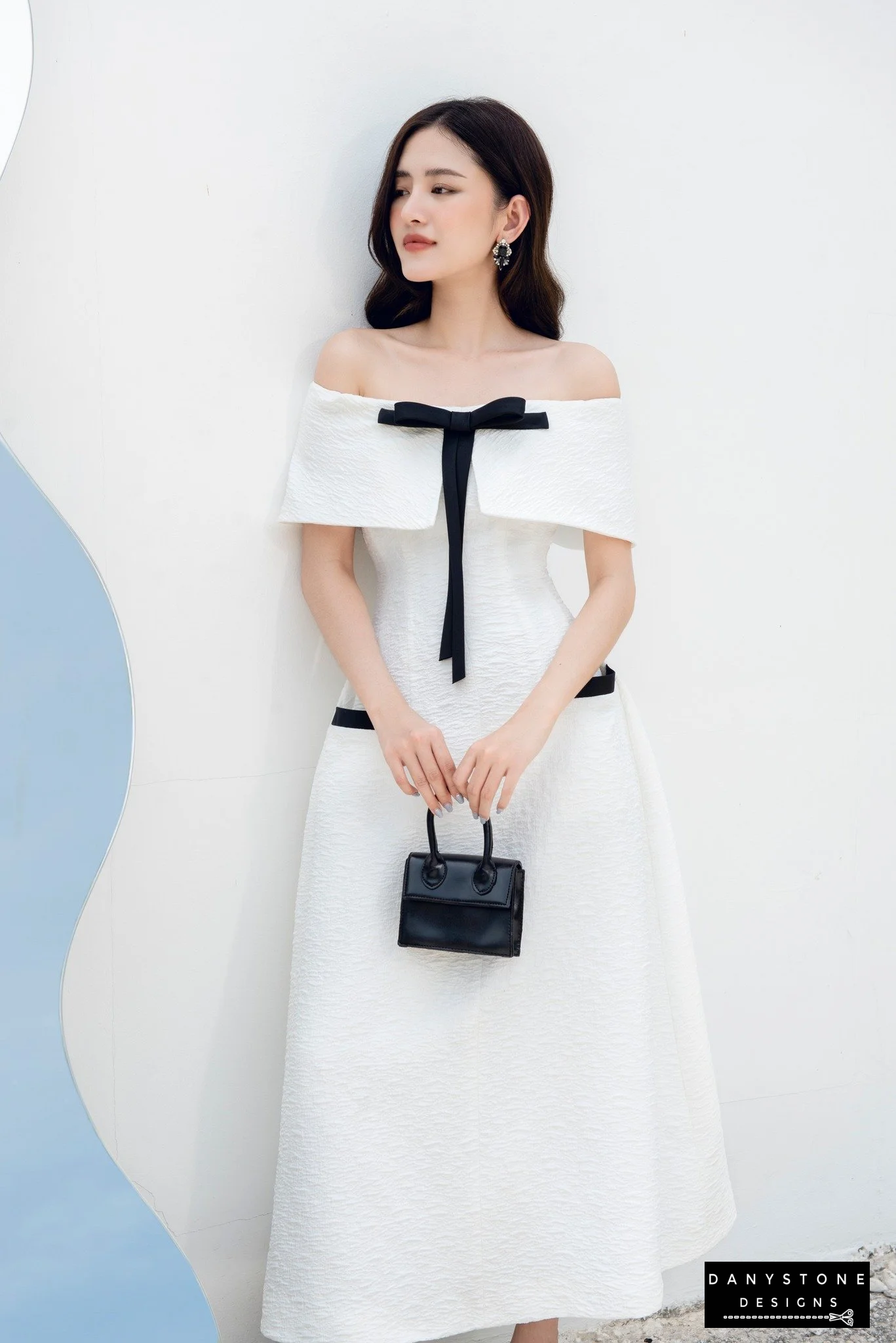 Model showcasing chic off-shoulder flared dress with chest bow in white