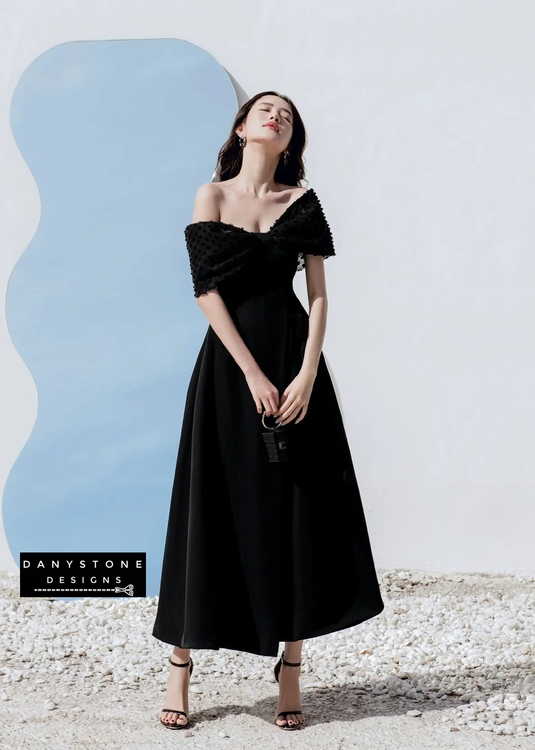 Model showcasing elegant off-shoulder bow flared dress with chiffon in Black