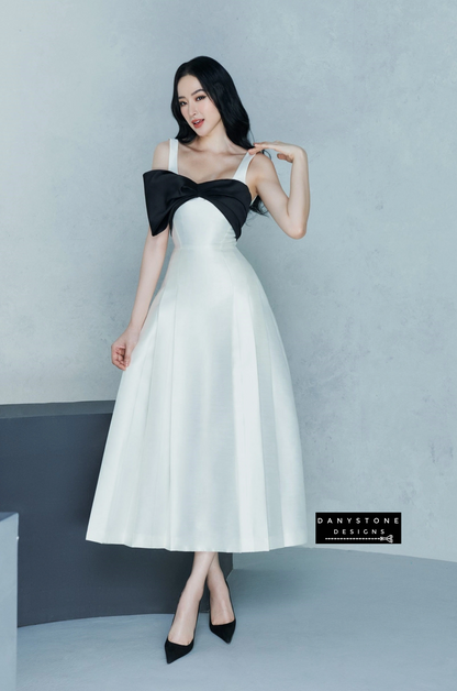 Detailed look at black bow on flared dress with 2 straps in white