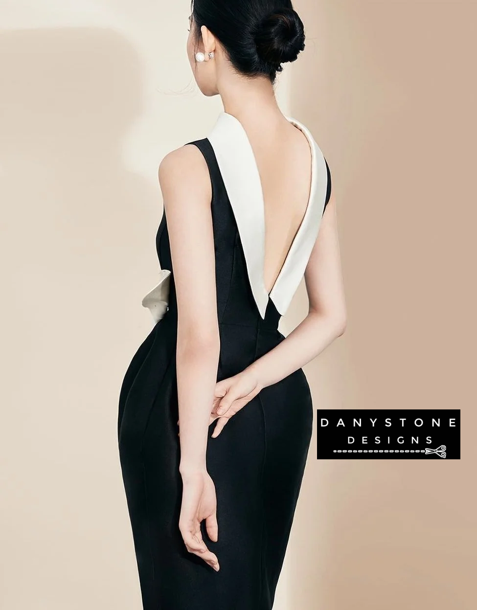 Model showcasing sophisticated black dress with white collar and floral detail