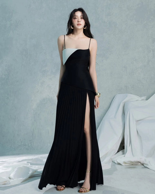 Woman wearing a black and white dress with a high slit on a gray background