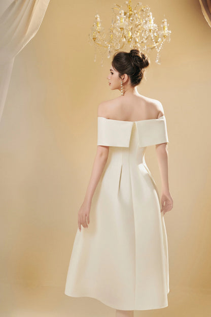 Woman wearing a white off-shoulder dress against a beige background