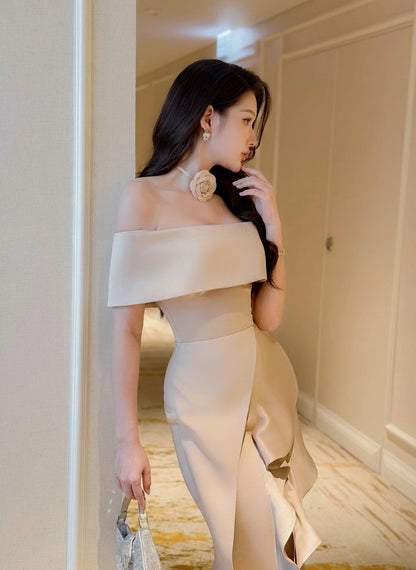 Woman in a beige off-shoulder dress standing in a room with neutral walls.
