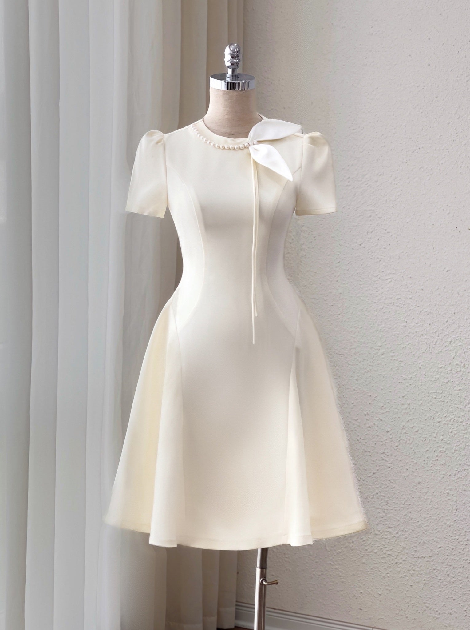 White dress on a mannequin against a plain background