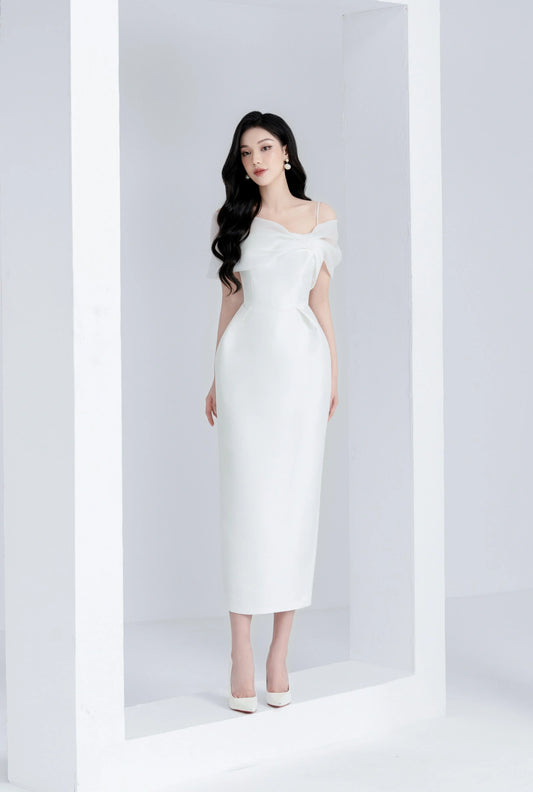 Woman in a white off-shoulder dress standing against a white background