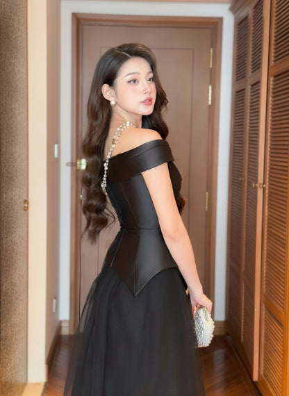 Woman in a black off-shoulder dress standing in a room with wooden doors.