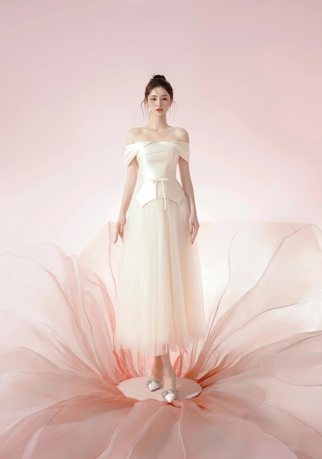 Woman wearing a light-colored off-shoulder dress with a soft pink background