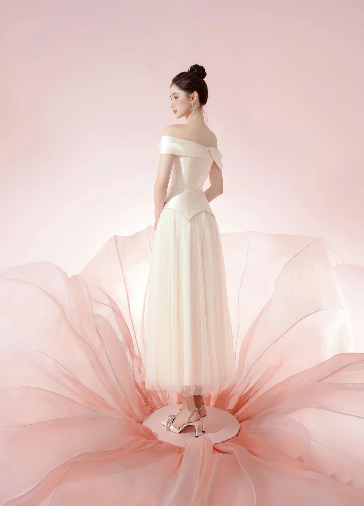 Woman in a white off-shoulder gown with a soft pink background