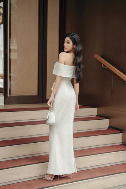 Woman in a white off-shoulder dress standing on steps