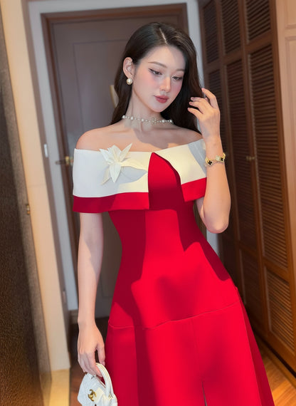 Woman in a red and white off-shoulder dress posing indoors.