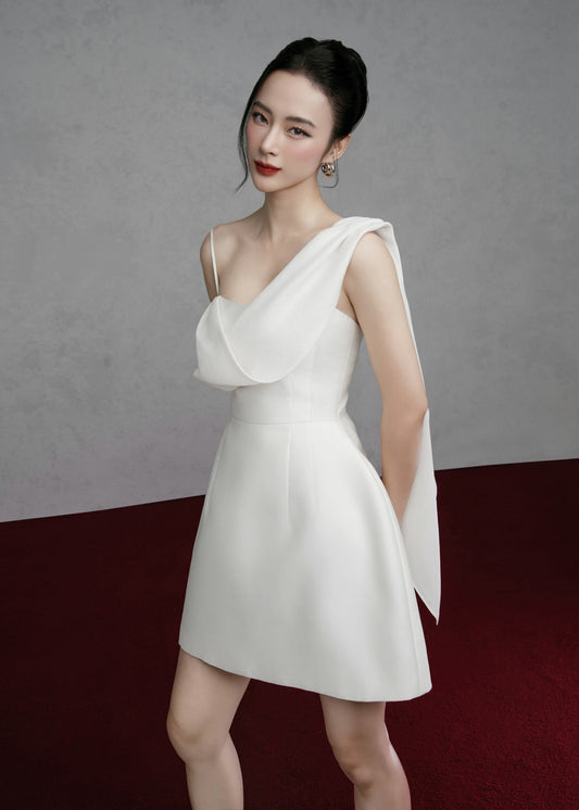 Woman wearing a white one-shoulder dress against a gray background