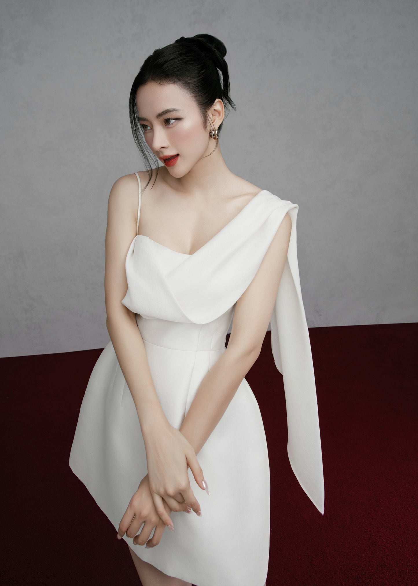 Woman in a white dress posing against a gray background
